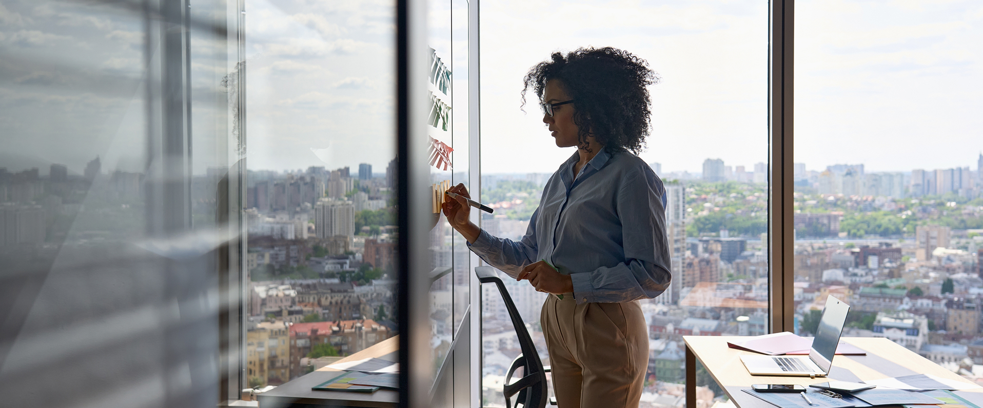 A woman in a business suit writes on a glass wall, symbolising podcast collaboration in a professional environment