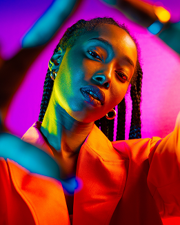A woman with braids stands in front of a vibrant background, representing a youth-led podcast channel